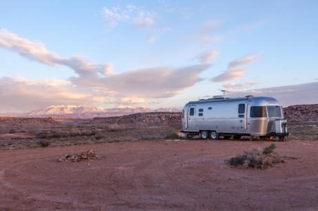 Grey RV parked in a desert at dusk.