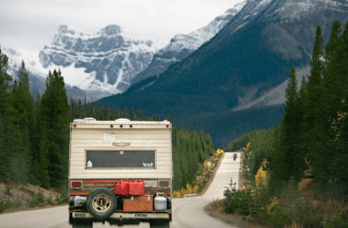 RV traveling down long highway stretch in a mountain environment.