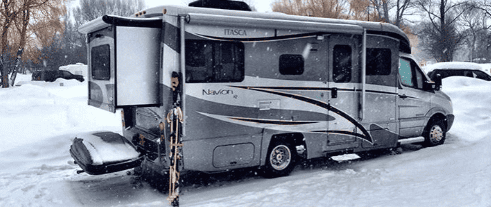 RV motorhome parked in a snowy campground.